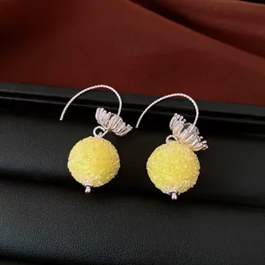 Close-up of elegant yellow beaded ball earrings with intricate silver flower caps