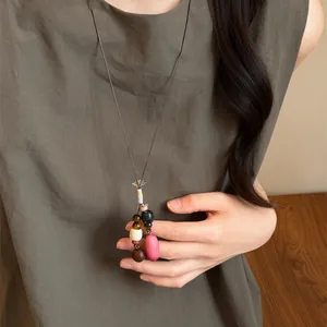 Close-up of handmade ethnic style long necklace with mixed beads and pink pendant