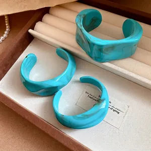 Set of three irregular marbled turquoise cuff bracelets displayed in a jewelry tray
