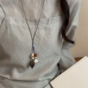 Handmade Mori style acorn pendant necklace worn over a linen top for a natural look.