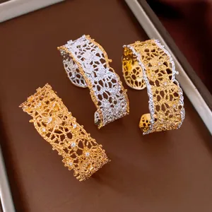 Close-up of lace hollowed-out metal cuff bracelets in gold and silver