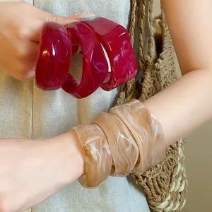 Detailed view of irregular marbled geometric resin bangles in vibrant red and beige colors.