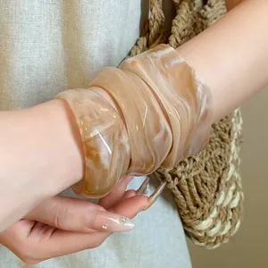 Close-up of layered irregular marbled bangles with a natural swirled finish on wrist.