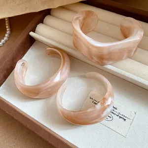 Detail view of irregular peach marbled resin cuff bangles in a display box