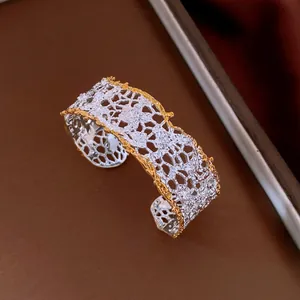 Close-up of two-tone hollow out lace cuff bracelet in gold and silver finish