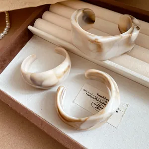 Close-up of irregular geometric resin bangles with brown marble ink pattern