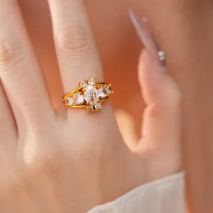 Detailed close-up of a luxury vintage gold ring with oval zircon stones on a finger.