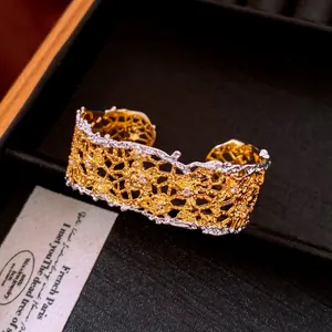 Close-up detail of luxury hollow lace cuff bracelet featuring gold and silver finish