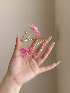 Detailansicht eines eleganten goldenen Armreifs mit rosa Emaille-Blumenanhängern.