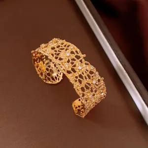 Close-up of a gold hollow lace bangle with sparkling crystal accents and intricate design