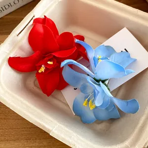Close-up of red and blue fabric flower hair clips in a rustic paper container box.