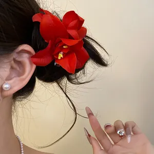Close-up of a large red fabric flower hair clip on dark hair for vacation style