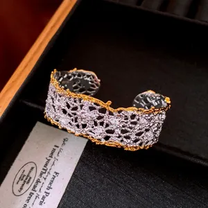 Close-up of elegant lace-style hollowed cuff bracelet with gold edges and crystals.