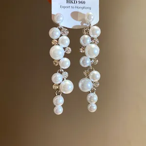 Detail view of silver needle tassel earrings with white pearls and sparkling rhinestones