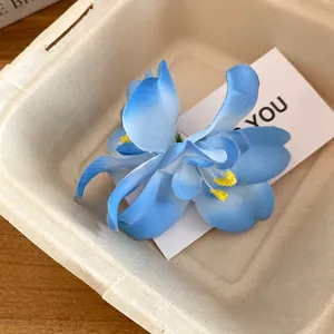 Macro detail of blue fabric flower hair clip presented in an elegant gift box packaging