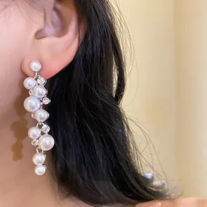 Close-up detail of elegant pearl and crystal tassel drop earrings worn by a model