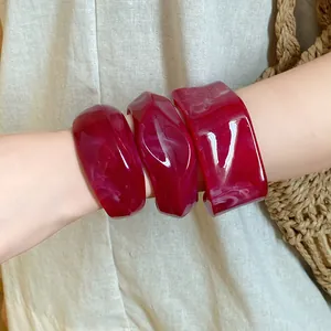 Detailed view of irregular geometric red marble resin open cuff bracelets worn on wrist
