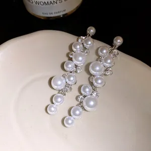 Close-up view of elegant long pearl earrings with sparkling rhinestone accents on tray