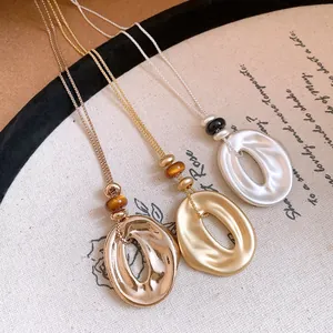 Detailansicht von drei Harzanhängern in Silber und Gold mit Faltenoptik und Perlen