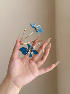 Detailansicht eines gedrehten goldenen Armreifs mit zwei blauen Emailleblumen