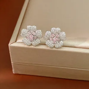 Elegant flower stud earrings featuring pink and white zircon stones on a jewelry box