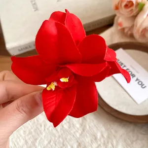 Close-up of a vibrant red fabric flower hair clip with realistic yellow stamens