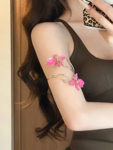 Detailaufnahme eines eleganten Oberarmreifs mit rosa Emaille-Blumen und Goldband