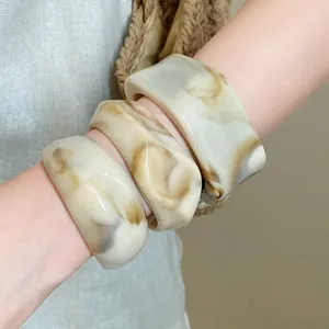 Detailed view of thick marbled resin bangles with an irregular geometric design