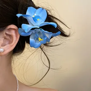 Detailed view of a vibrant blue fabric flower hair clip on a elegant bun hairstyle