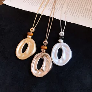 Nahaufnahme von drei minimalistischen Halsketten mit zerknitterten Harzanhängern in Gold und Silber.
