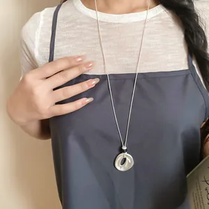 Nahaufnahme einer eleganten Harzkette mit rundem Anhänger an einem Model