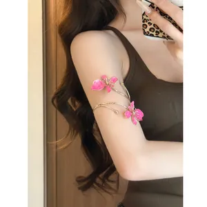 Nahaufnahme eines stilvollen goldenen Armreifs mit rosa Emaille-Blumen an einem Model.