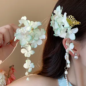 Dettaglio di fermaglio per capelli a fiore in tessuto con nappe di perle e clip oro