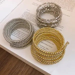 Detailed view of multi-layer spiral wrap bracelets with gold and silver metallic beads.
