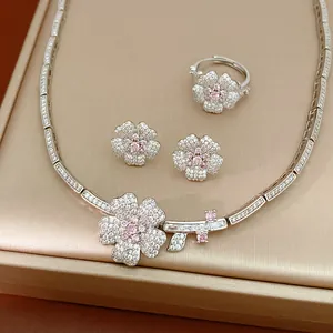 Detailed view of a luxury silver flower necklace, earrings, and ring set with pink zircon.