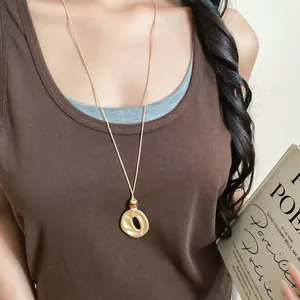 Detailansicht einer Halskette mit faltigem Harzanhänger an einer langen goldenen Kette