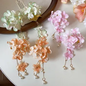 Vista dettagliata di fermagli per capelli con fiori di stoffa, nappe e perle eleganti.