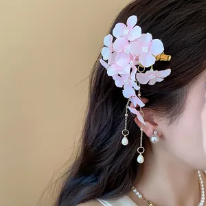 Primo piano di un fermaglio per capelli a fiore in tessuto rosa con nappe di perle