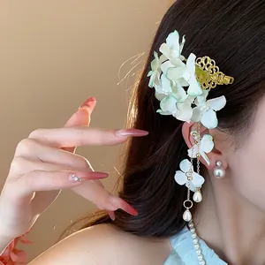 Dettaglio di una molletta per capelli a fiori in tessuto con eleganti nappe di perle.