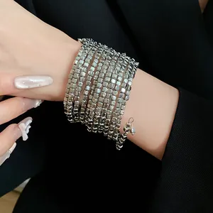 Detail view of a silver multi-layered wrap bracelet worn on a wrist with black blazer