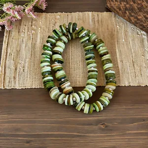 A close-up view of a vintage ethnic shell beaded necklace with multi-tone green beads.