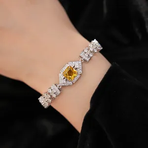 Detailed view of a luxury zircon bracelet with a central yellow square gemstone on a wrist.