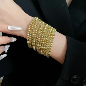 Close-up detail of multi-layer golden bead wrap bracelet worn on a model's wrist.