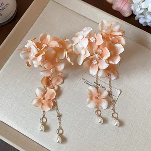Dettaglio di eleganti fermagli per capelli a fiori con nappe di perle su base di lino.