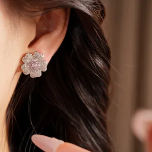 Macro detail of a sparkling zircon flower stud earring worn on a model's ear