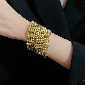 Close-up detail of a layered gold beaded bracelet worn with a professional blazer