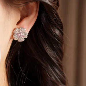 Detailed view of elegant sparkling zircon flower stud earrings with pink center on ear