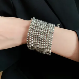 Close-up detail of multi-layer silver beaded wrap bracelet styled with a chic black blazer.