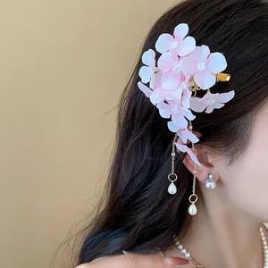 Dettaglio di un'elegante molletta per capelli con fiore rosa e nappe di perle su capelli mossi
