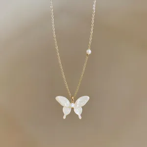 Detailed view of an elegant gold necklace featuring a white butterfly pendant and pearl